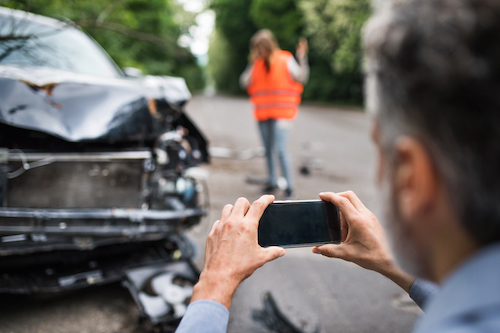 man taking pictures of a car after accident