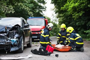 Firefighters helping a young injured woman after a car accident.