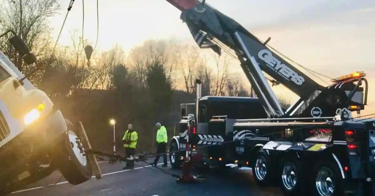 Geyers recovery truck lifting a disabled truck at a roadside scene