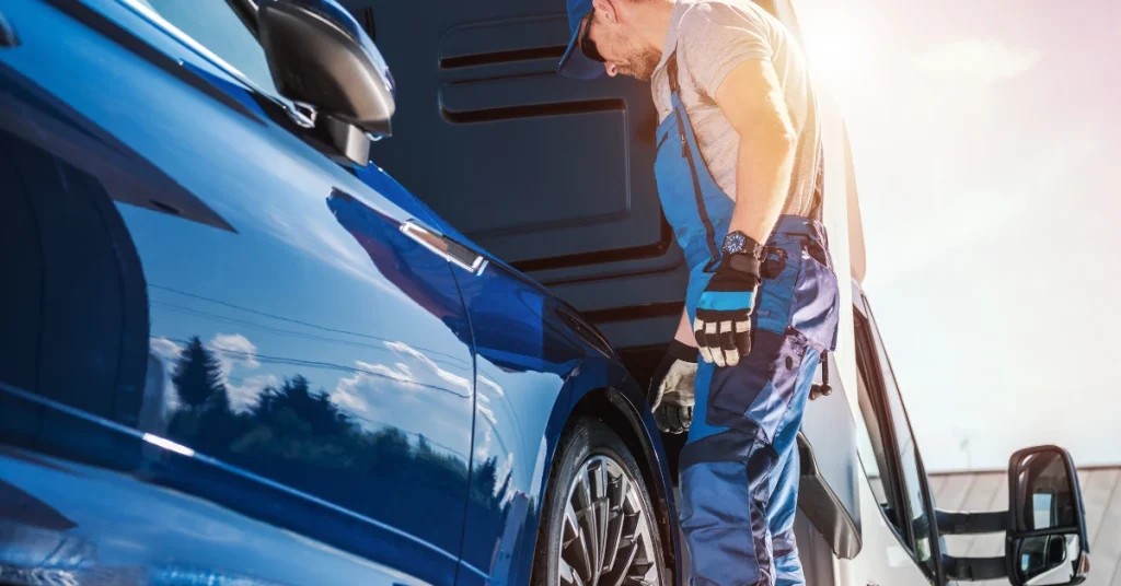 Worker in uniform inspecting a blue car before auto transport