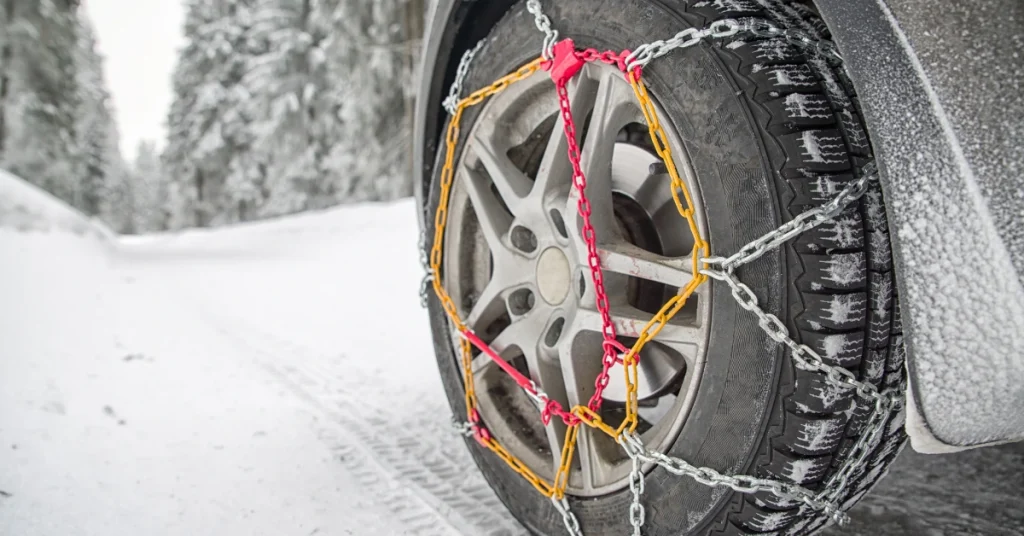 Car tire with snow chains driving on an icy road