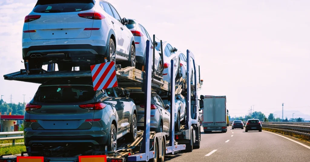 Open car transport trailer carrying multiple vehicles