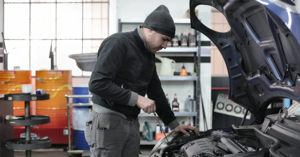 Mechanic inspecting a car engine in an auto repair shop.