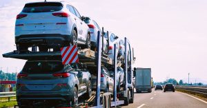 Loaded car hauler trailer transporting multiple SUVs on an open highway, part of long-distance vehicle transport or dealership delivery fleet