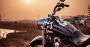 Close-up of a Harley-Davidson motorcycle parked near a rural road at sunset, symbolizing a roadside breakdown and the need for towing assistance.
