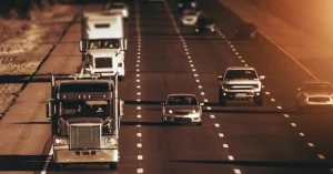 Trucks and cars on an interstate, the road open and enclosed car transport carriers share